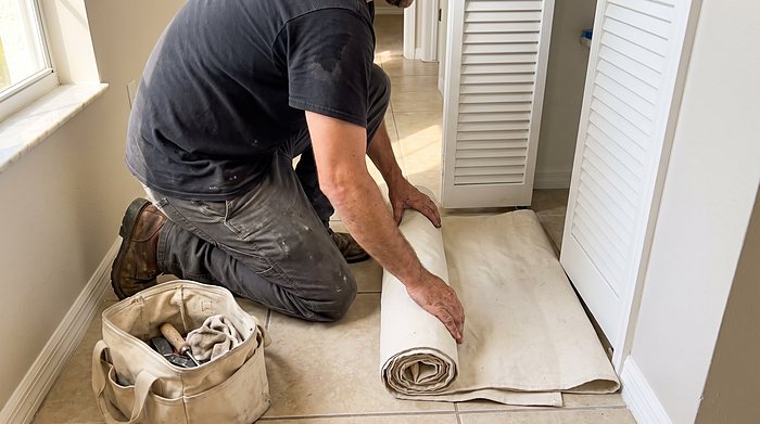 A technician lays a canvas drop cloth on the floor before starting work