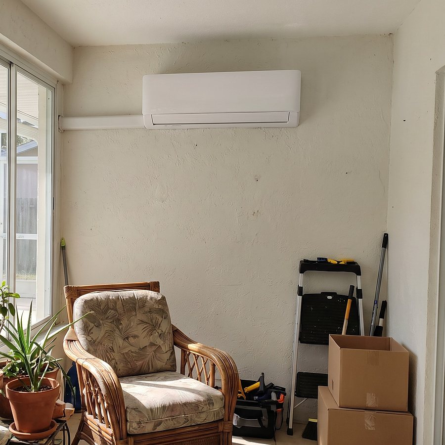 A ductless mini-split head mounted high on a sunroom wall