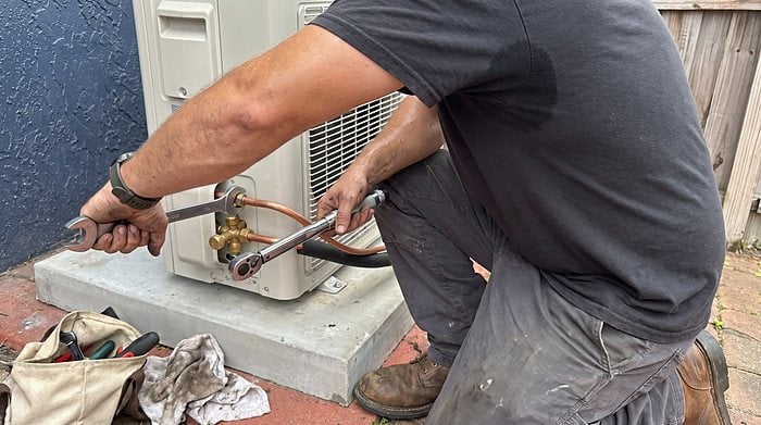 A technician tightens a flare fitting on a mini-split line set