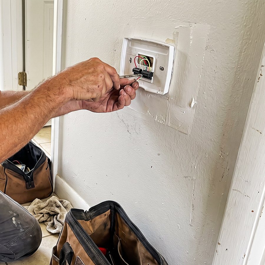 A technician fits a new thermostat to the wall