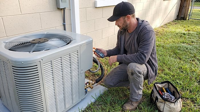 A technician checks the refrigerant lines at a heat pump outdoor unit