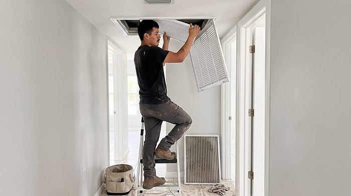 A technician replaces the filter in a hallway ceiling return