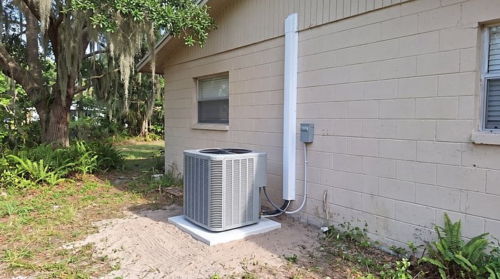 A new air conditioning condenser on a concrete pad beside a block home in Central Florida