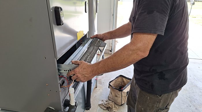 A technician fits the filter rack on a closet air handler