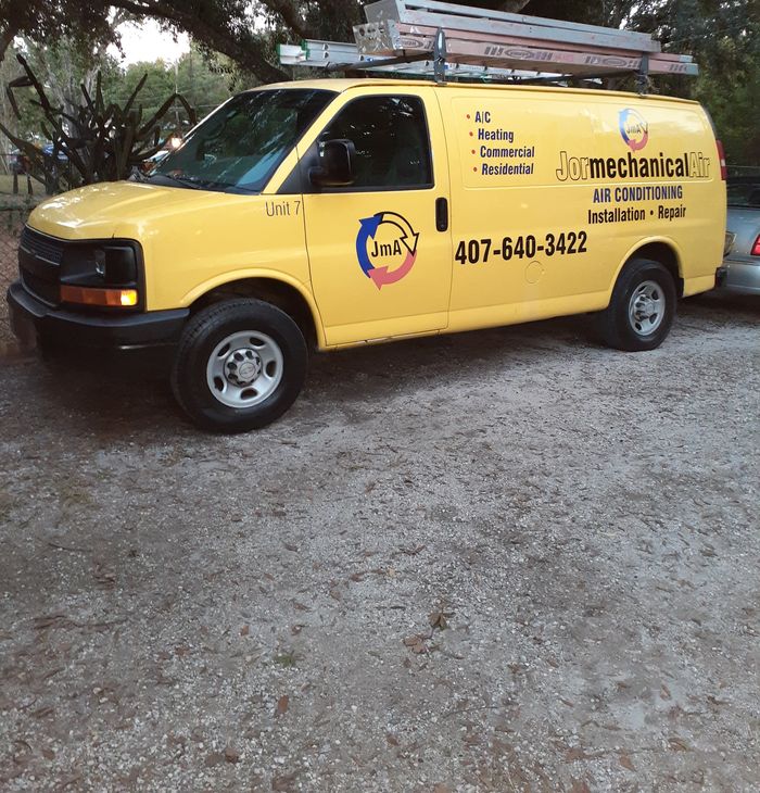 The yellow Jormechanical Air van parked under oak trees